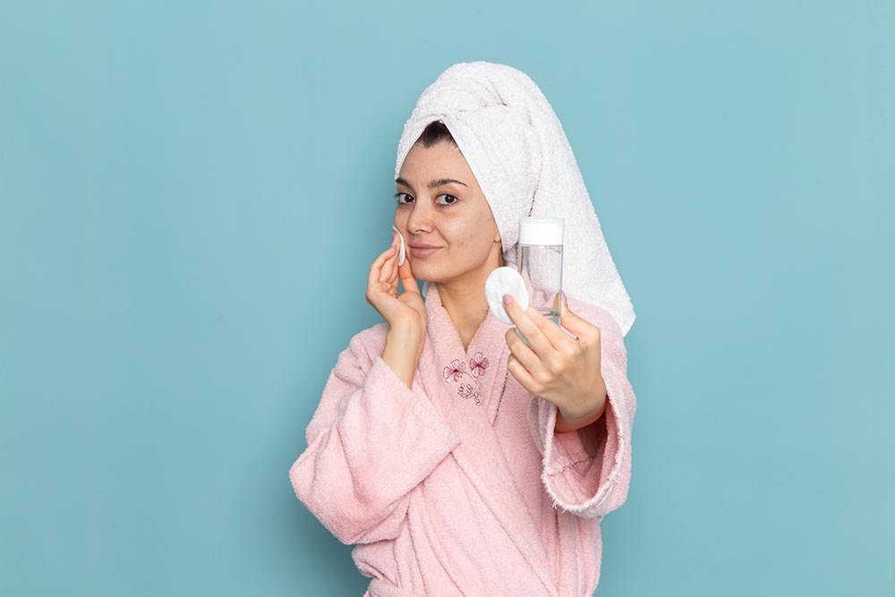 front view young female pink bathrobe holding spray blue wall cleaning beauty clean water selfcare cream shower