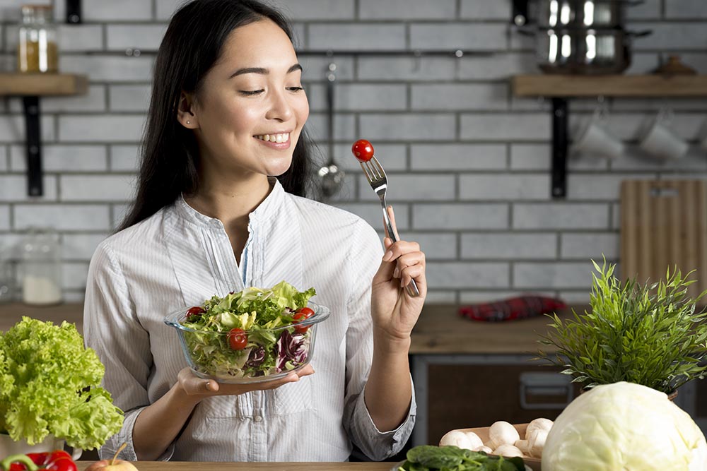 smiling asian woman with healthy salad kitchen
