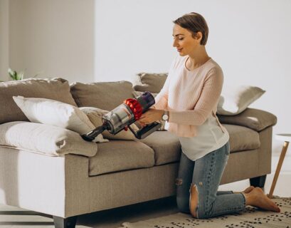 young woman with rechargeable vacuum cleaner cleaning home