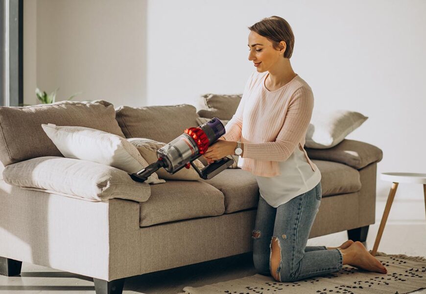 young woman with rechargeable vacuum cleaner cleaning home