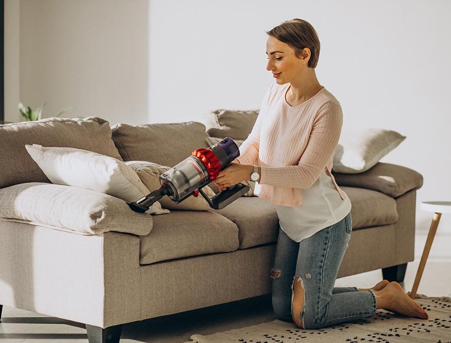 young woman with rechargeable vacuum cleaner cleaning home